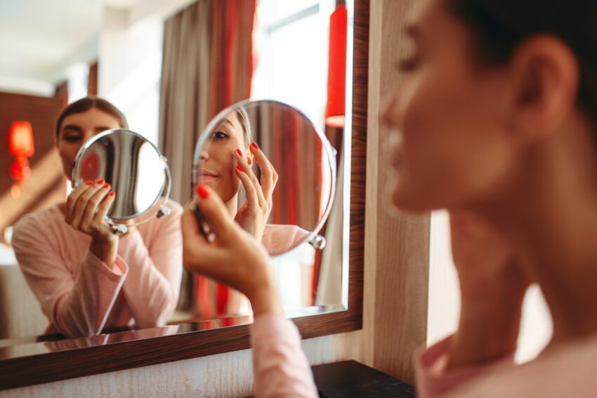 Woman doing makeup at the mirror, face hygiene
